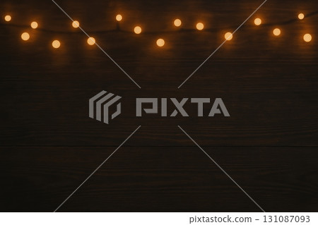 Warm string lights hanging on dark wooden background for festive decoration Warm string lights hanging on dark wooden background for festive decoration 131087093