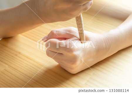 Pressing acupressure points on the hand with a pressure stick - Hegu stock photo 131088114