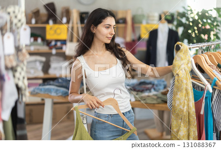 Woman on sale choosing dresses and tops in the store Woman on sale choosing dresses and tops in the store 131088367