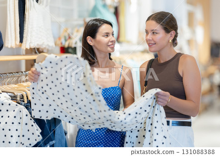 Two young women choosing a dress and other clothes in clothing store Two young women choosing a dress and other clothes in clothing store 131088388