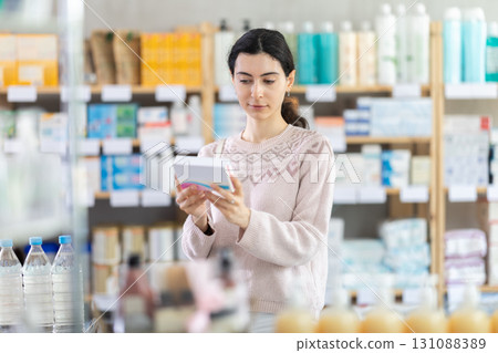 Young woman choosing boxes of pills in pharmacy 131088389