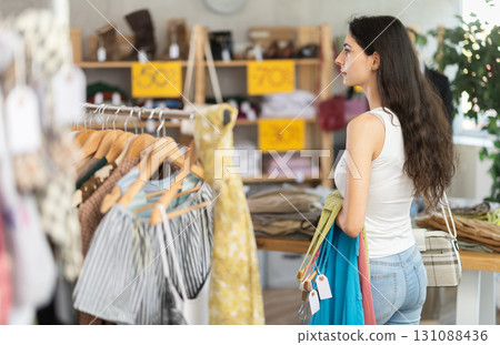 Woman on sale choosing dresses and tops in the store 131088436
