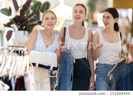 Three women choosing trousers and vest in clothing store 131088444