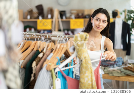 Young woman customer elect something summer clothes in store. 131088506