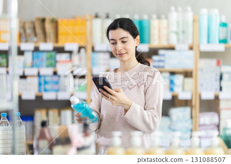 Girl in autumn clothes scans code on medicinal mouthwash to check expiration date Girl in autumn clothes scans code on medicinal mouthwash to check expiration date 131088507