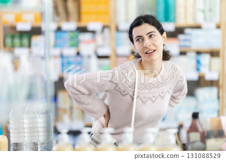 Woman holding her lower back in pharmacy 131088529