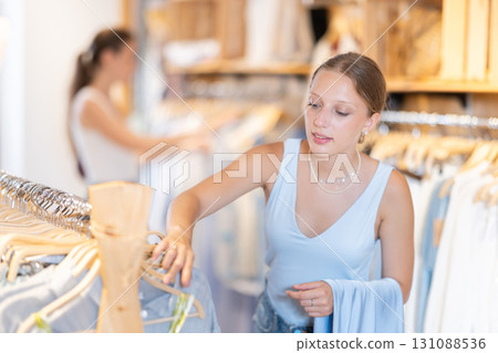 Young girl chooses something in branded clothing store 131088536