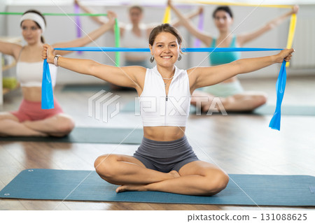 Group of women doing exercises with resistance bends in fitness room Group of women doing exercises with resistance bends in fitness room 131088625