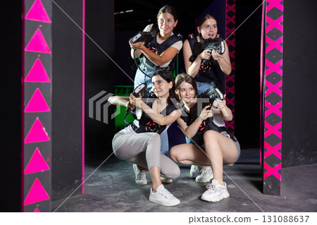Four happy girls with laser pistols in their hands in dark laser tag room 131088637