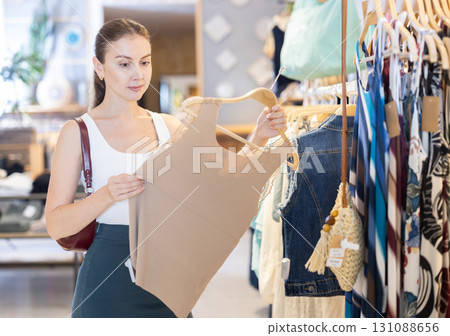 Girl customer chooses singlet blouse in branded store Girl customer chooses singlet blouse in branded store 131088656