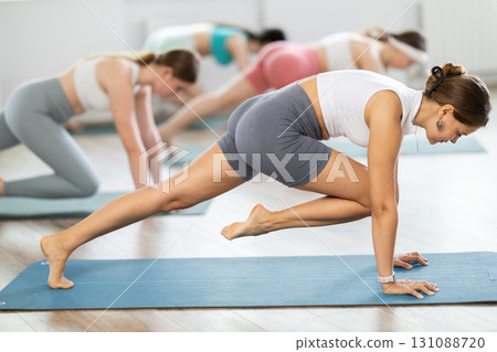 Young girl practicing one-legged plank position in pilates studio 131088720