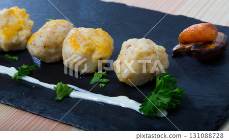 Dumplings of different white fish served with carrot at plate on table 131088728