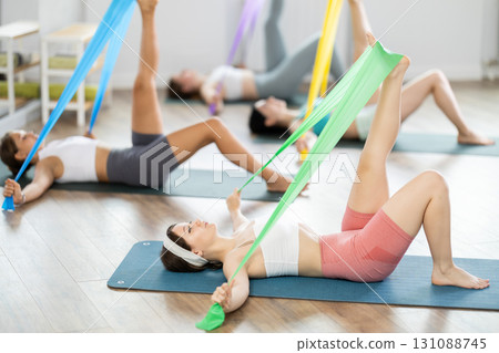 Young girl practicing leg stretching with band lying on back 131088745