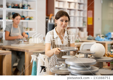 Young girl puts pottery wheel for clay modeling Young girl puts pottery wheel for clay modeling 131088751