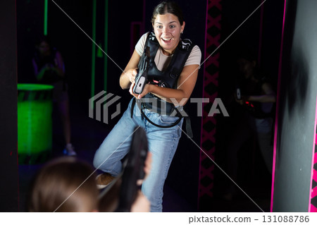 Young lady having fun playing lasertag in labyrinth Young lady having fun playing lasertag in labyrinth 131088786