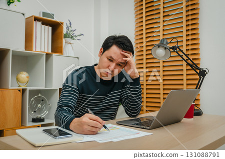 stressed man working with document and laptop at home office 131088791