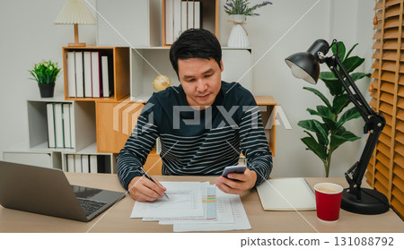 business man using smartphone and writing document. working at home office business man using smartphone and writing document. working at home office 131088792