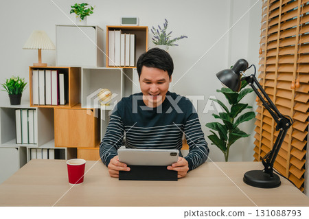 happy man watching digital tablet at home office 131088793