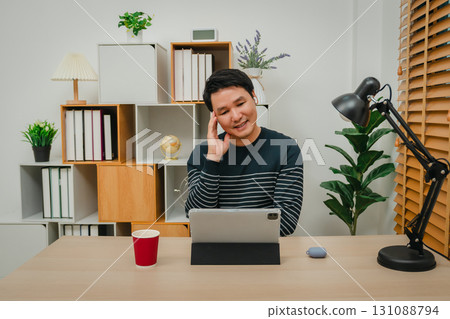 happy man using wireless earbuds to listening music and tablet at home office happy man using wireless earbuds to listening music and tablet at home office 131088794