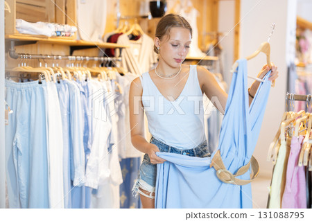 Girl customer chooses dress in branded store 131088795