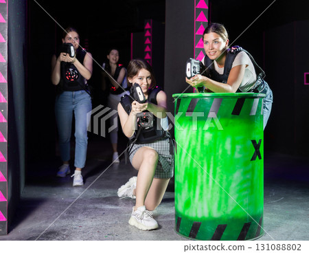 Team of young girlfriends play laser tag in labyrinth. Girls spend time actively 131088802
