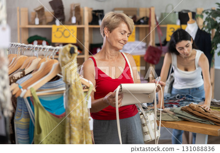 Senior woman customer elect leather handbag in store. Female client choosing something in background 131088836