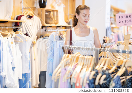 Girl customer chooses blouse in branded store 131088838