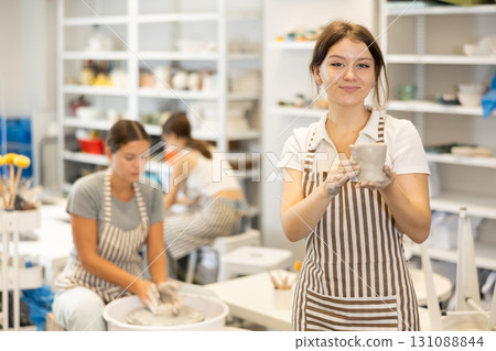 Young girl with handmade ceramic cup in workshop 131088844