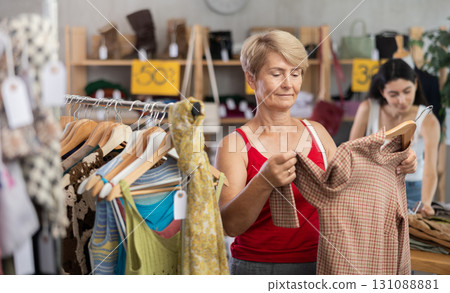 Mature woman choosing a brown sweater Mature woman choosing a brown sweater 131088881