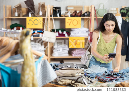 woman with long hair is eating at the counter with pants and scanning a barcode 131088883