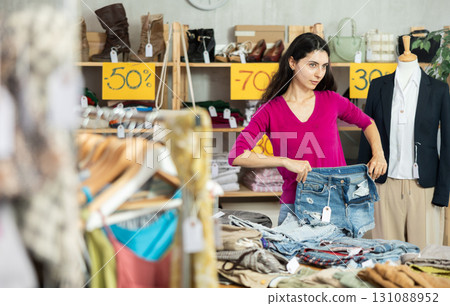 Woman with black hair choosing pants in a store Woman with black hair choosing pants in a store 131088952