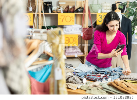 woman with long hair is eating at the counter with pants and scanning a barcode 131088985