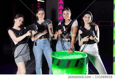Four cheerful and happy girls pose in locker room before laser tag match. Four cheerful and happy girls pose in locker room before laser tag match. 131089039