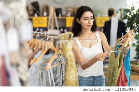 Woman on sale choosing dresses and tops in the store 131089048