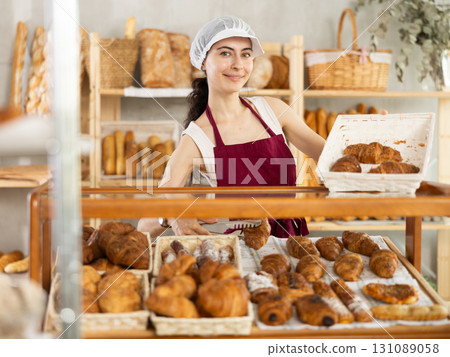 Young woman seller puts croissants in showcase Young woman seller puts croissants in showcase 131089058