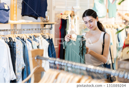 Girl customer chooses blouse in branded store Girl customer chooses blouse in branded store 131089204