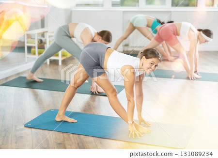 Young female teacher working out practice Parshvottanasana with students group 131089234