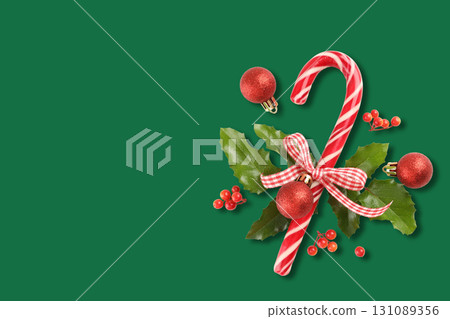 Festive candy cane surrounded by red ornaments and holly 131089356