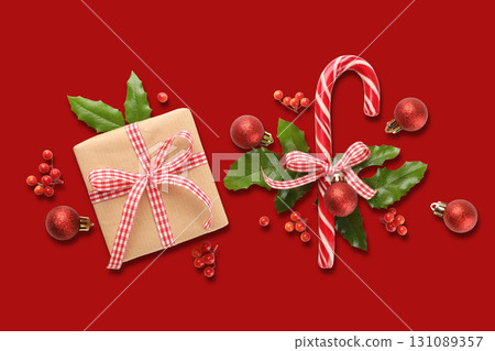 A gift box with a bow and a candy cane among Christmas ornaments A gift box with a bow and a candy cane among Christmas ornaments 131089357