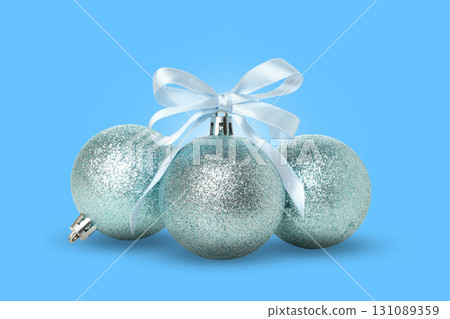 Three shiny blue Christmas ornaments tied with a ribbon 131089359