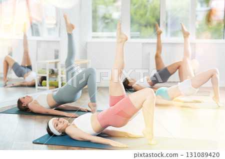 Young girls practicing one legged bridge position in pilates studio Young girls practicing one legged bridge position in pilates studio 131089420