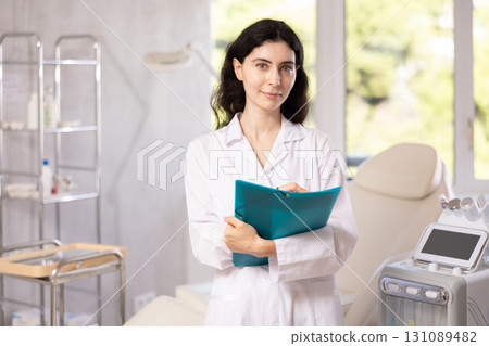 Female doctor assistant standing in medical office making notes on clipboard Female doctor assistant standing in medical office making notes on clipboard 131089482