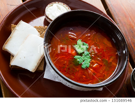 Ukrainian borscht red-beet soup on bowl, served with bread and salo 131089546