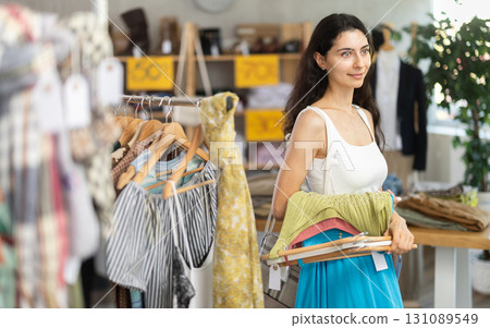 Woman on sale choosing dresses and tops in the store 131089549