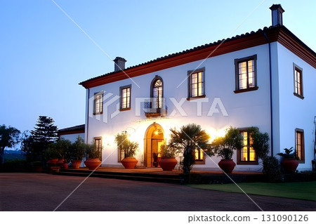 Elegant Estate House at Dusk with Warm Lighting and Lush Landsca 131090126