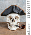 Detailed View of Pirate Skull with Smoking Pipe and Hat on Rustic Wooden Surface 131091477