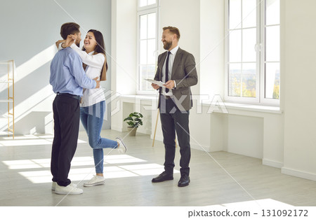 Woman holding home keys while hugging boyfriend in their new apartment after buying real estate. 131092172