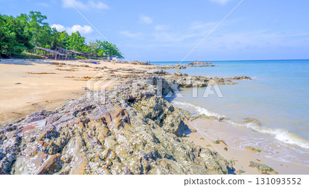 Tropical rocky beach with sandy shore, green trees, and blue ocean Tropical rocky beach with sandy shore, green trees, and blue ocean 131093552