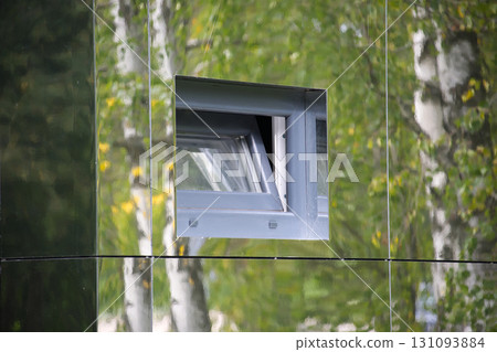 Modern Reflective Building Facade with a Small Open Window and Natural Reflections Modern Reflective Building Facade with a Small Open Window and Natural Reflections 131093884