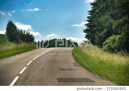 Scenic Rural Road Amid Verdant Fields and Lush Forest Under Clear Blue Sky Scenic Rural Road Amid Verdant Fields and Lush Forest Under Clear Blue Sky 131093885